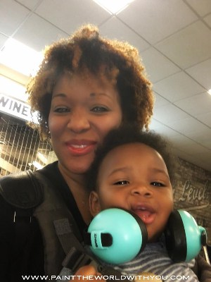 Mom and toddler at airport.  Toddler wearing blue Banz headphones.