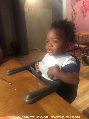 A toddler at a restaurant in portable high chair.