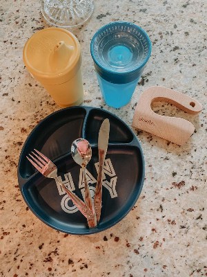 Toddler essentials, suction plate, utensils, mini cutter and yellow and blue sippy cups.