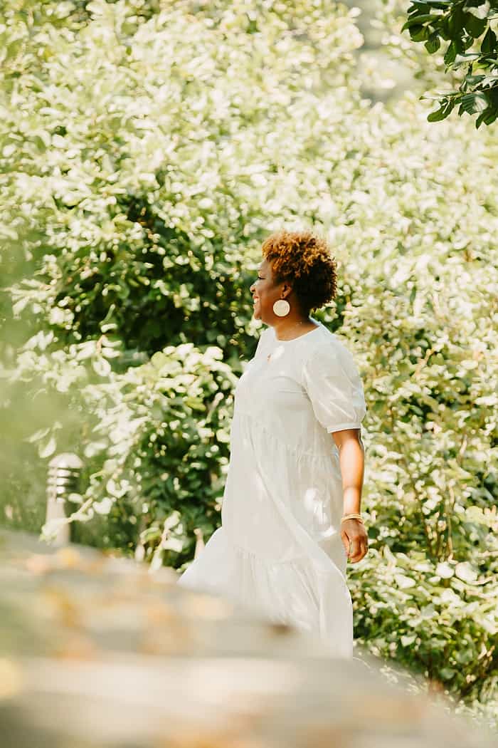 Mother in white dress looking at trees.