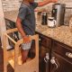 Toddler on a kitchen helper tower starting a coffee machine