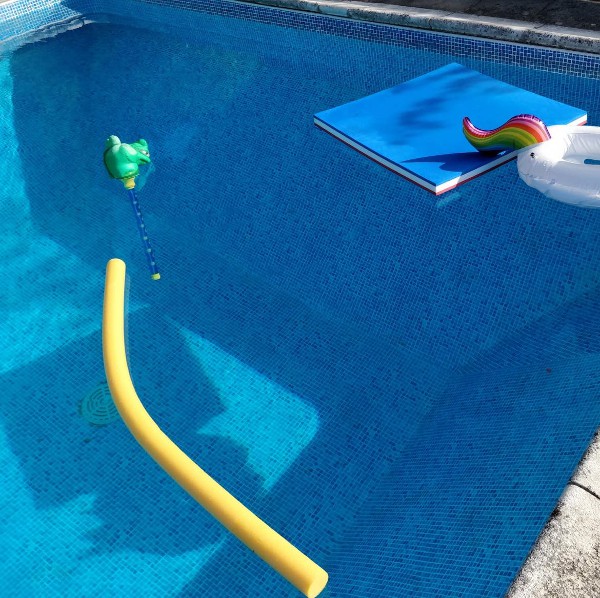 A pool with a unicorn float and a noodle.