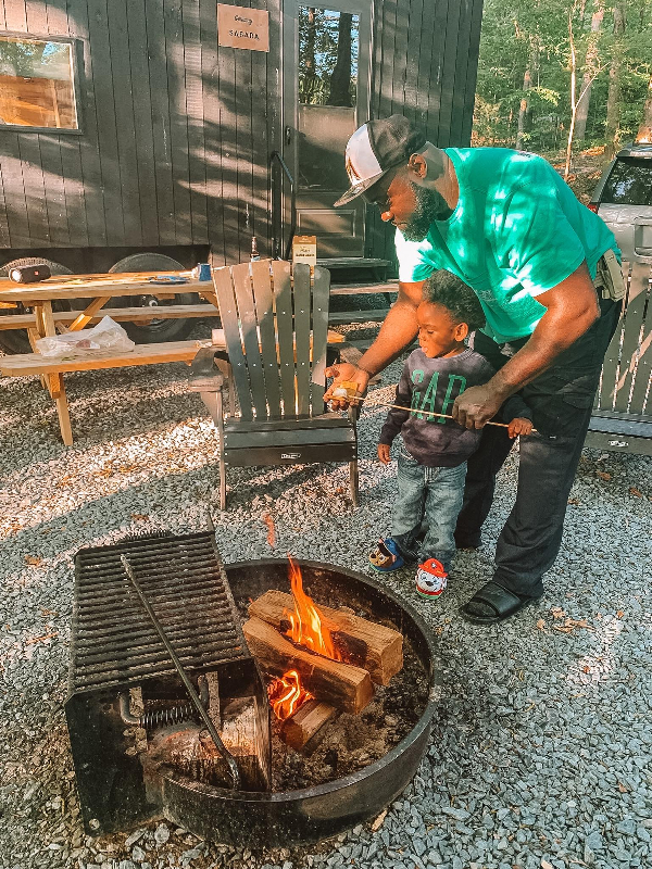 Father and son at camp site making s'mores over a camp fire.