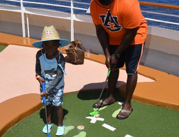 Father and son playing golf on a disney cruise.