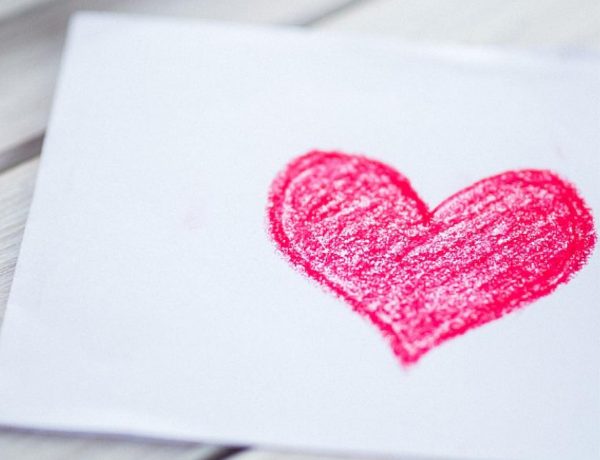 Pink heart on a piece of paper and crayons.