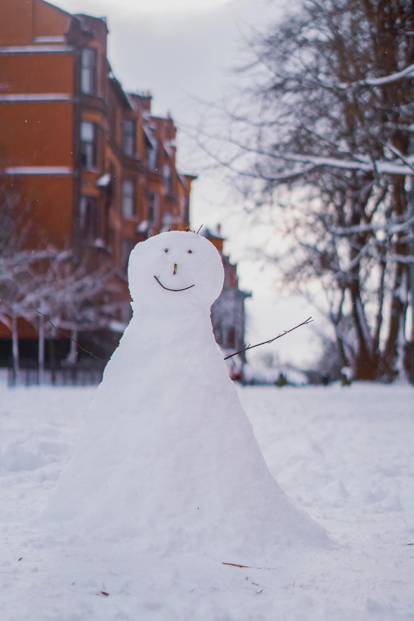 Snowman in front of a building.